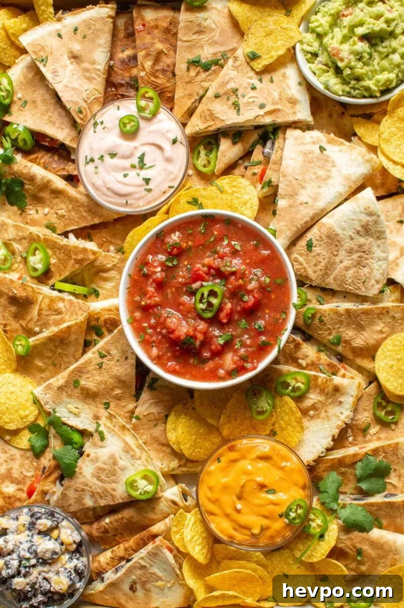 How to Style a Show-Stopping Quesadilla Platter for Entertaining 2 Closeup of a wooden platter with salsas and quesadillas and corn chips arranged over it.