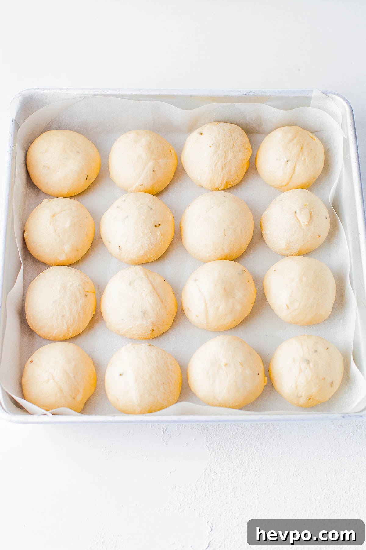 Raw garlic herb rolls in a parchment paper lined baking dish. 