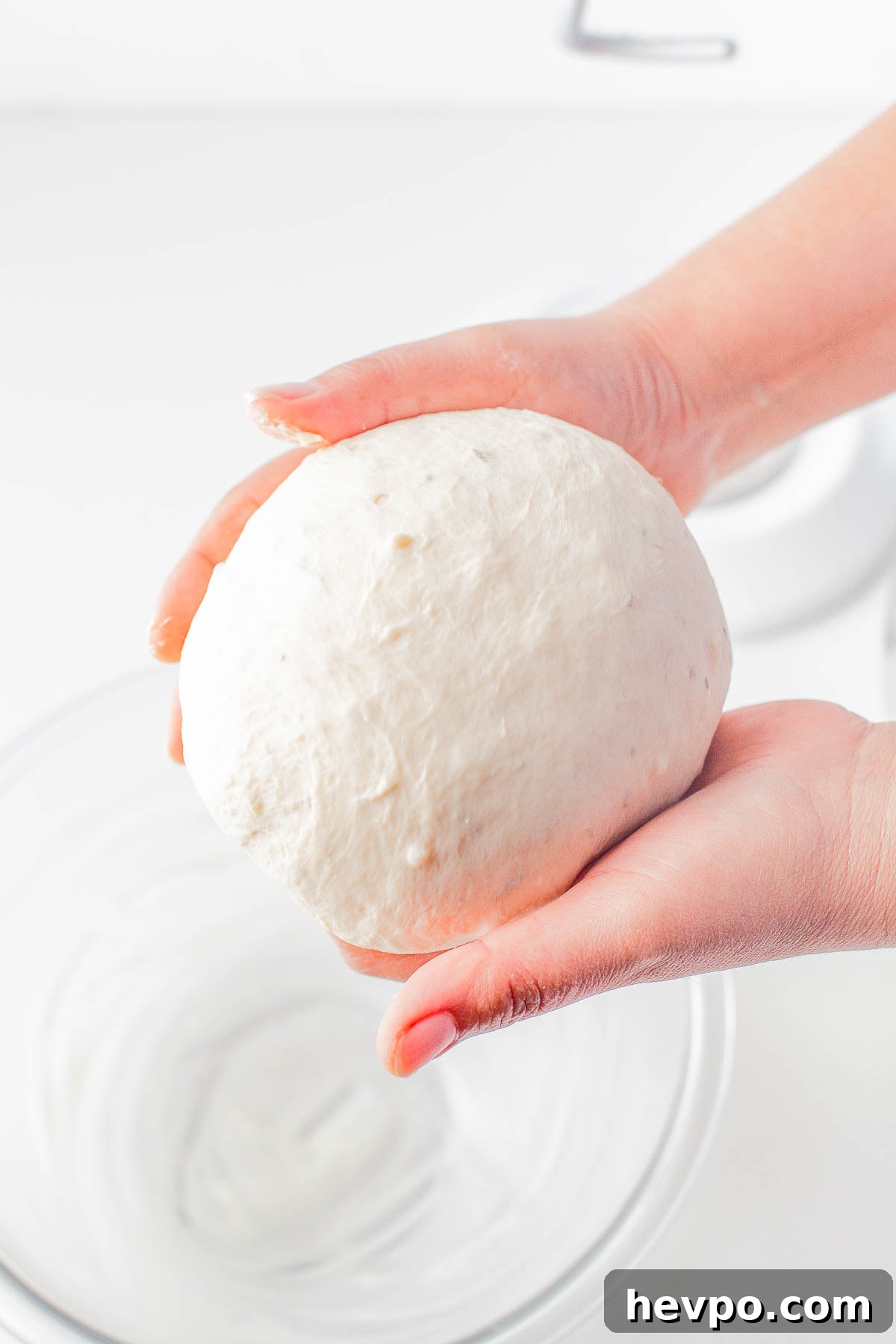 Two hands shaping dough for garlic herb rolls. 