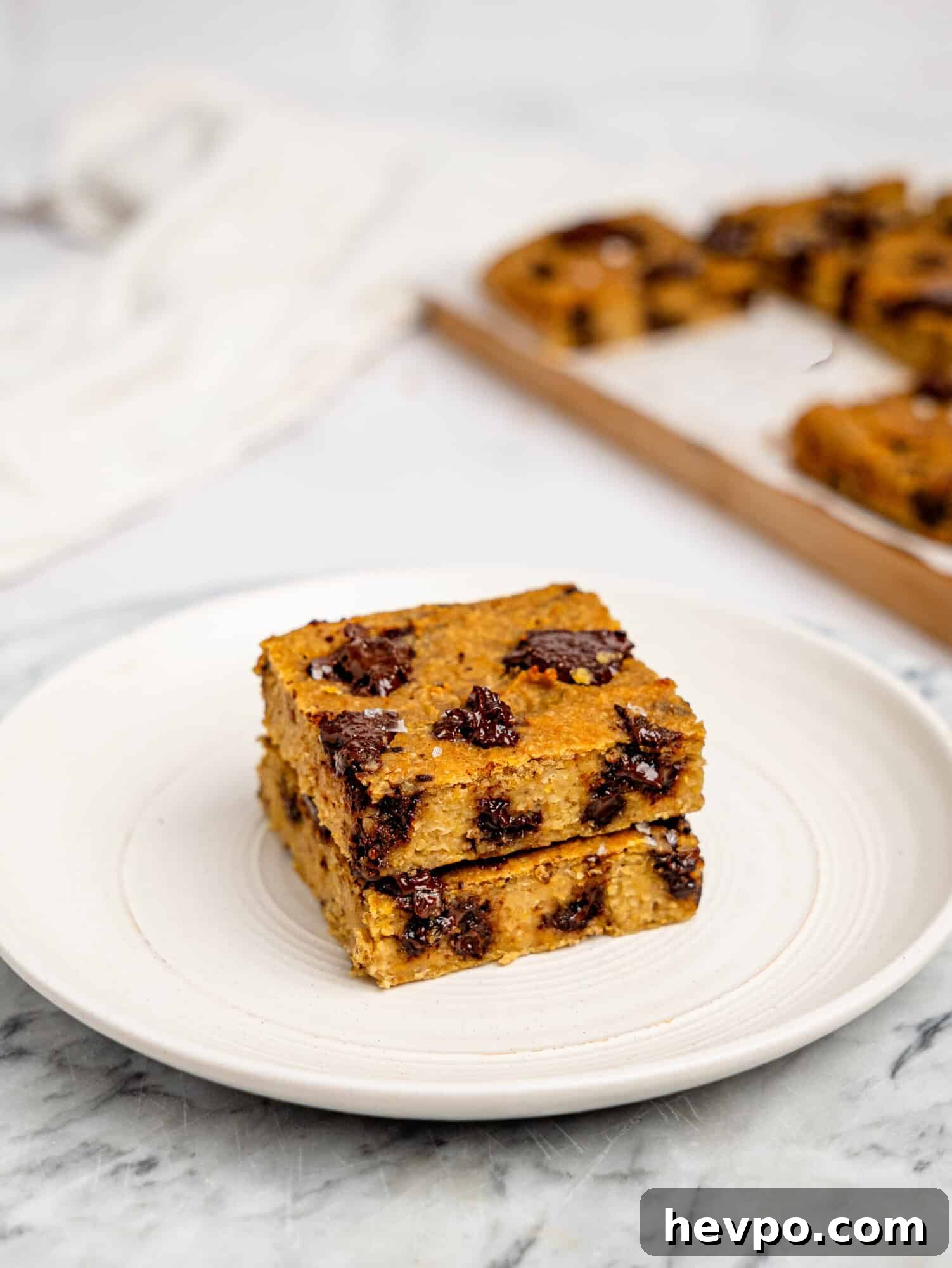 Chewy Chickpea Cookie Bars with Gooey Chocolate Swirls 5 Two chickpea cookie bars stacked on top of each other on a white plate.