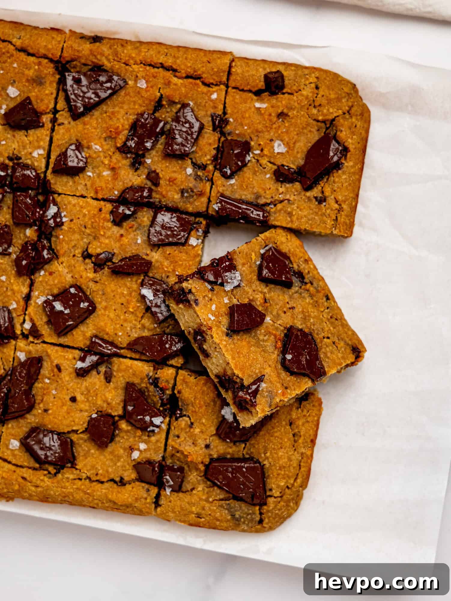 Chewy Chickpea Cookie Bars with Gooey Chocolate Swirls 9 Bird's eye view of chickpea cookie bars on a sheet of white parchment paper.