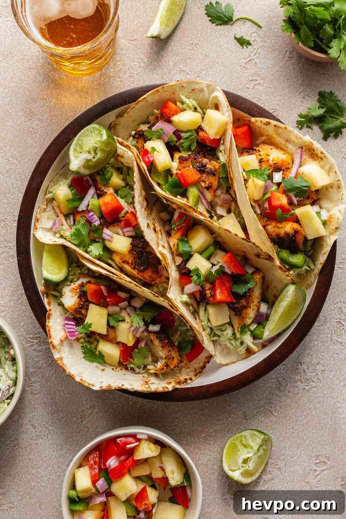 Crispy Air Fryer Fish Tacos with Tangy Slaw and Lime 2 Fish tacos topped with pineapple salsa and arranged in a round serving dish.