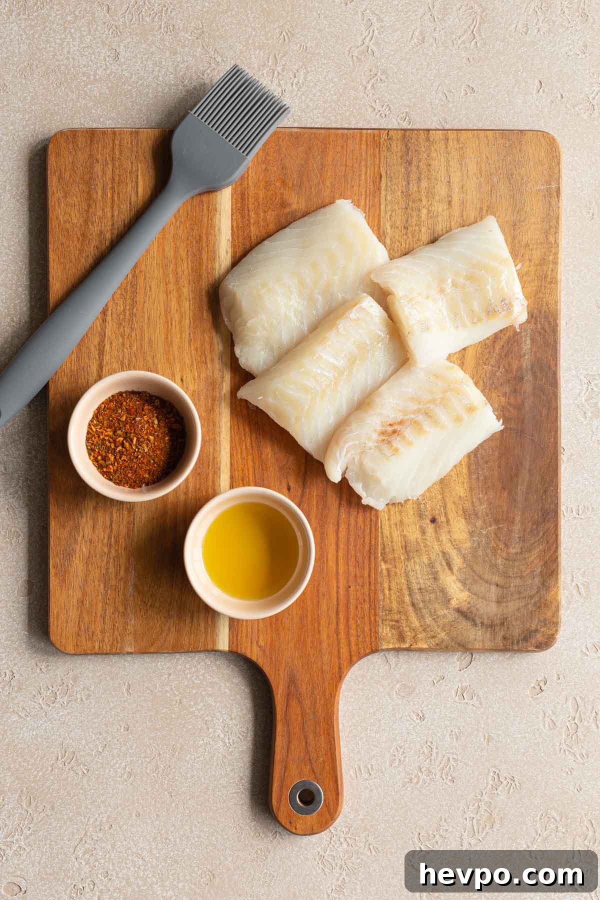 Crispy Air Fryer Fish Tacos with Tangy Slaw and Lime 3 Cajun seasoning, oil and raw fish fillet pieces on a wooden cutting board.