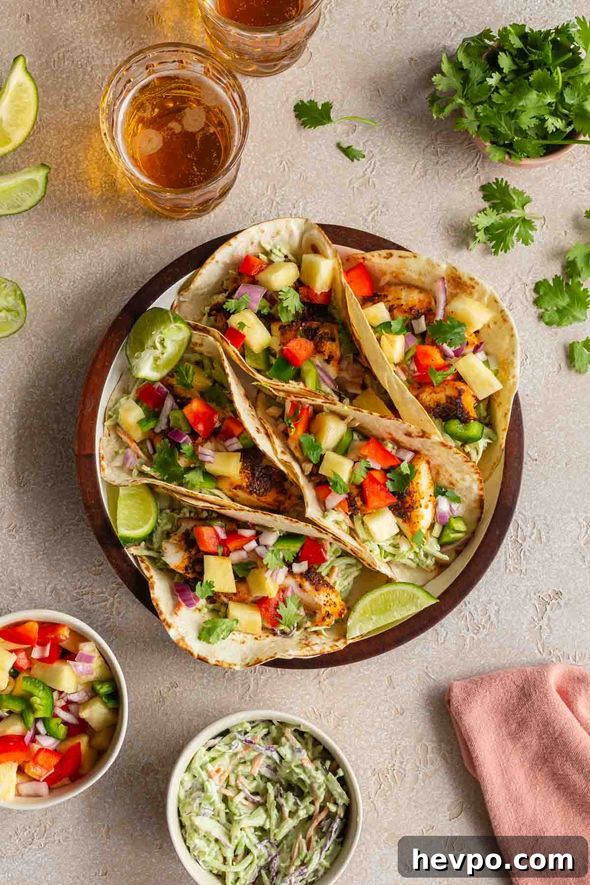Crispy Air Fryer Fish Tacos with Tangy Slaw and Lime 7 Overhead of fish tacos on a round plate with beer, slaw, cilantro and salsa off to the sides.