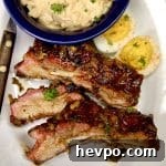 3 ribs on a plate with deviled eggs, potato salad.