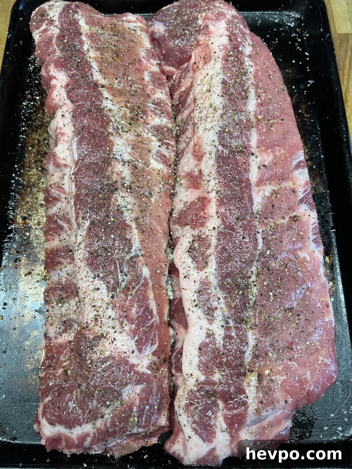 2 racks ribs on a sheet pan with salt & pepper.