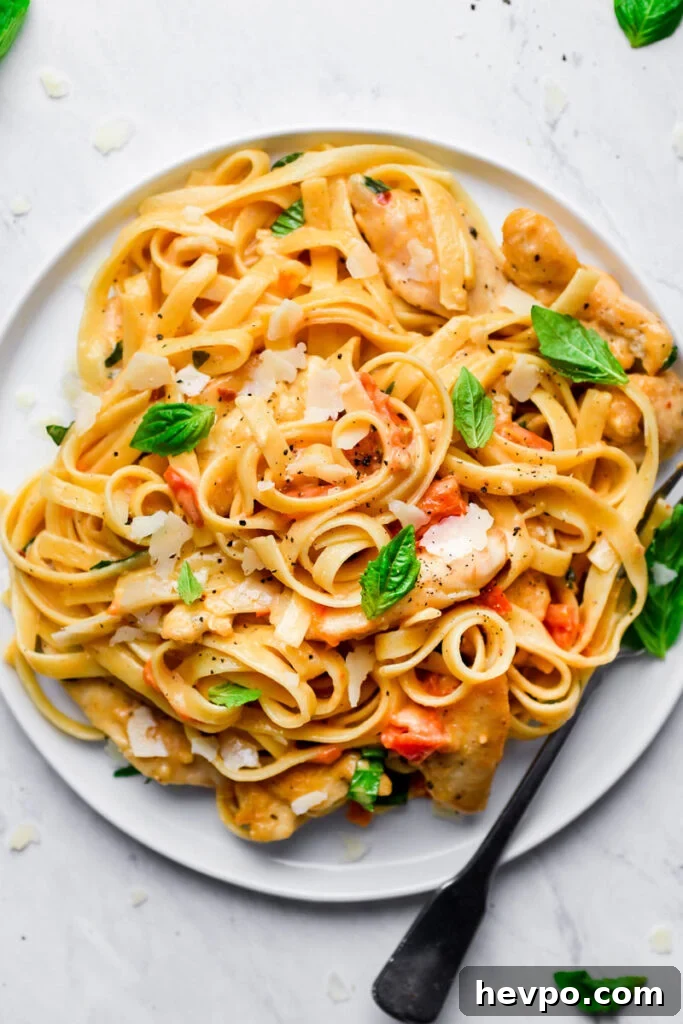 tomato basil pasta served on a white plate with a fork on the side