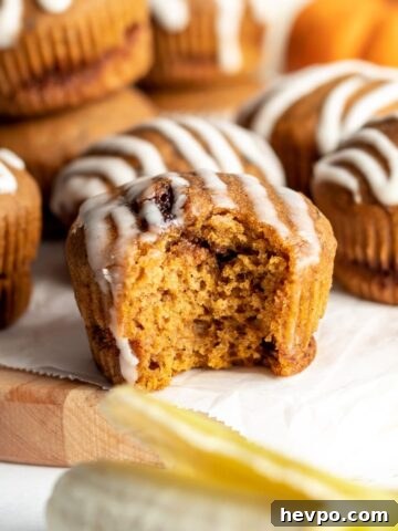 A pumpkin muffin topped with icing with a bite taken out of it.