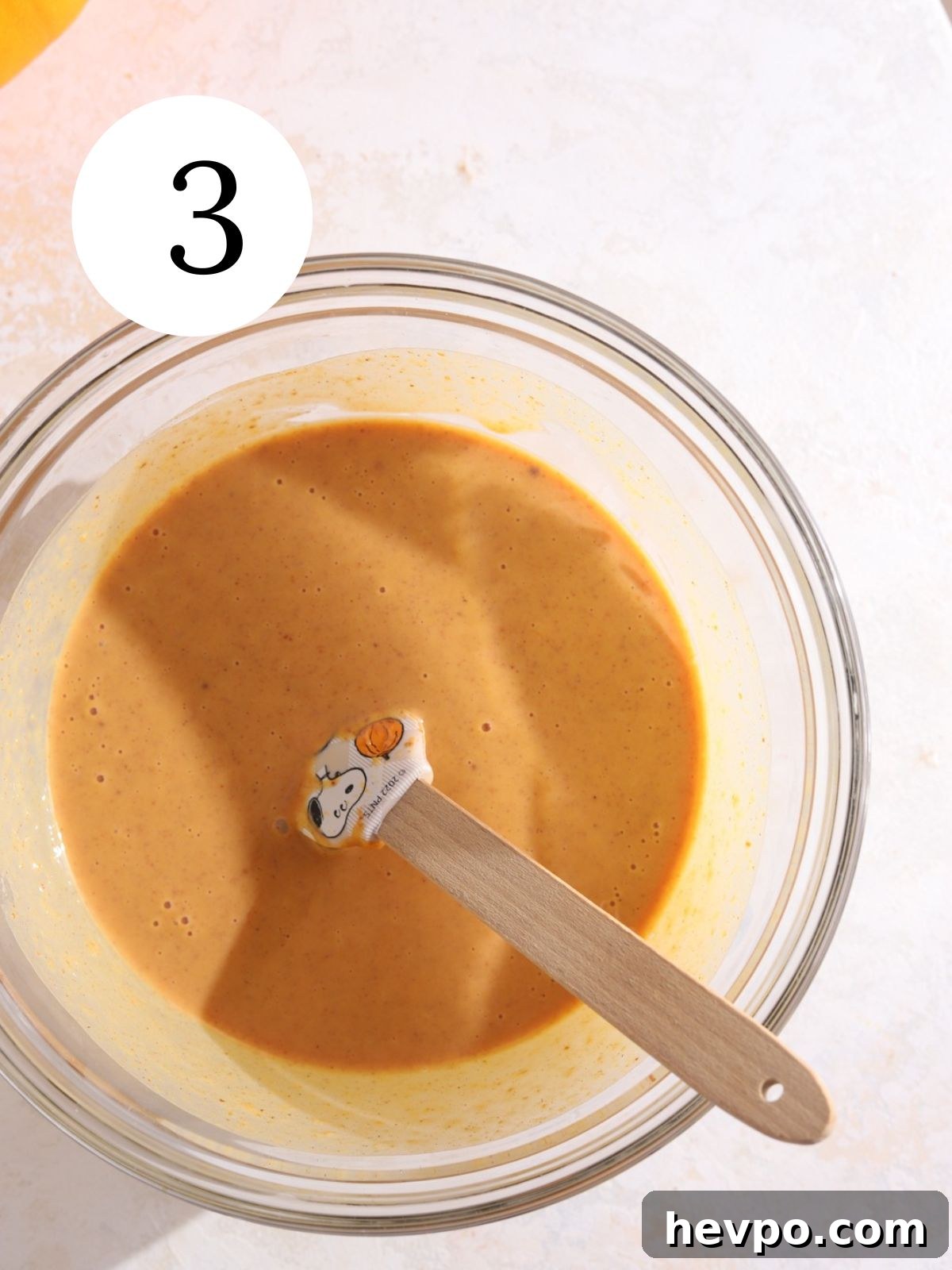 Creamy Pumpkin Ice Cream Recipe for Fall Desserts 6 A glass bowl with an orange pumpkin mixture and a mini spatula in it.