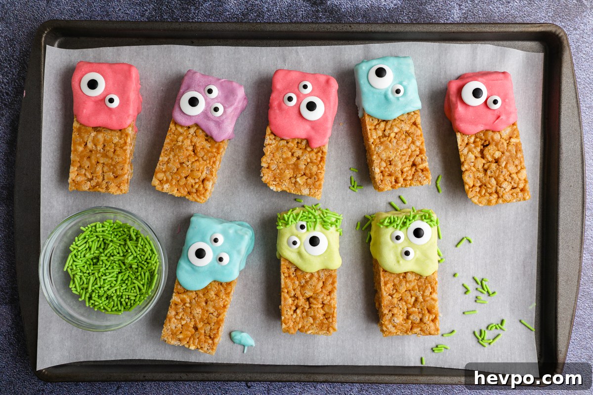 Spooky Halloween Rice Krispie Treats for Kids and Parties 4 Peanut butter rice krispie treats decorated for Halloween sitting on a tray lined with parchment paper