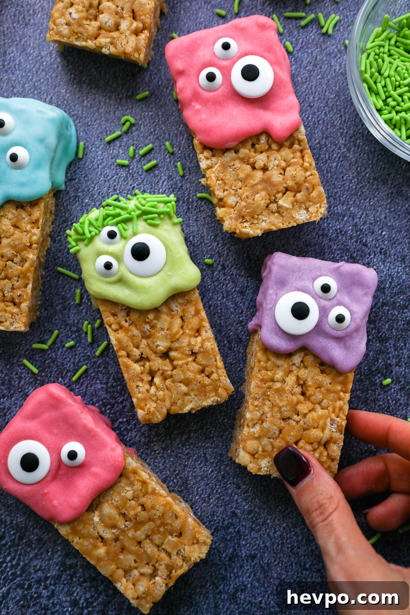 Spooky Halloween Rice Krispie Treats for Kids and Parties 6 A hand reaching for a Halloween decorated rice krispie treat