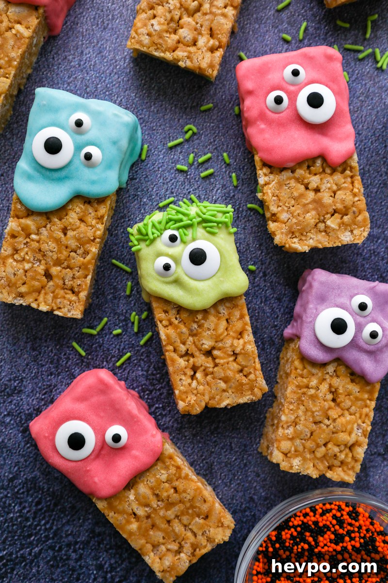 Spooky Halloween Rice Krispie Treats for Kids and Parties 7 Halloween rice krispie treats laying on a blue board surrounded by green, orange and black sprinkles
