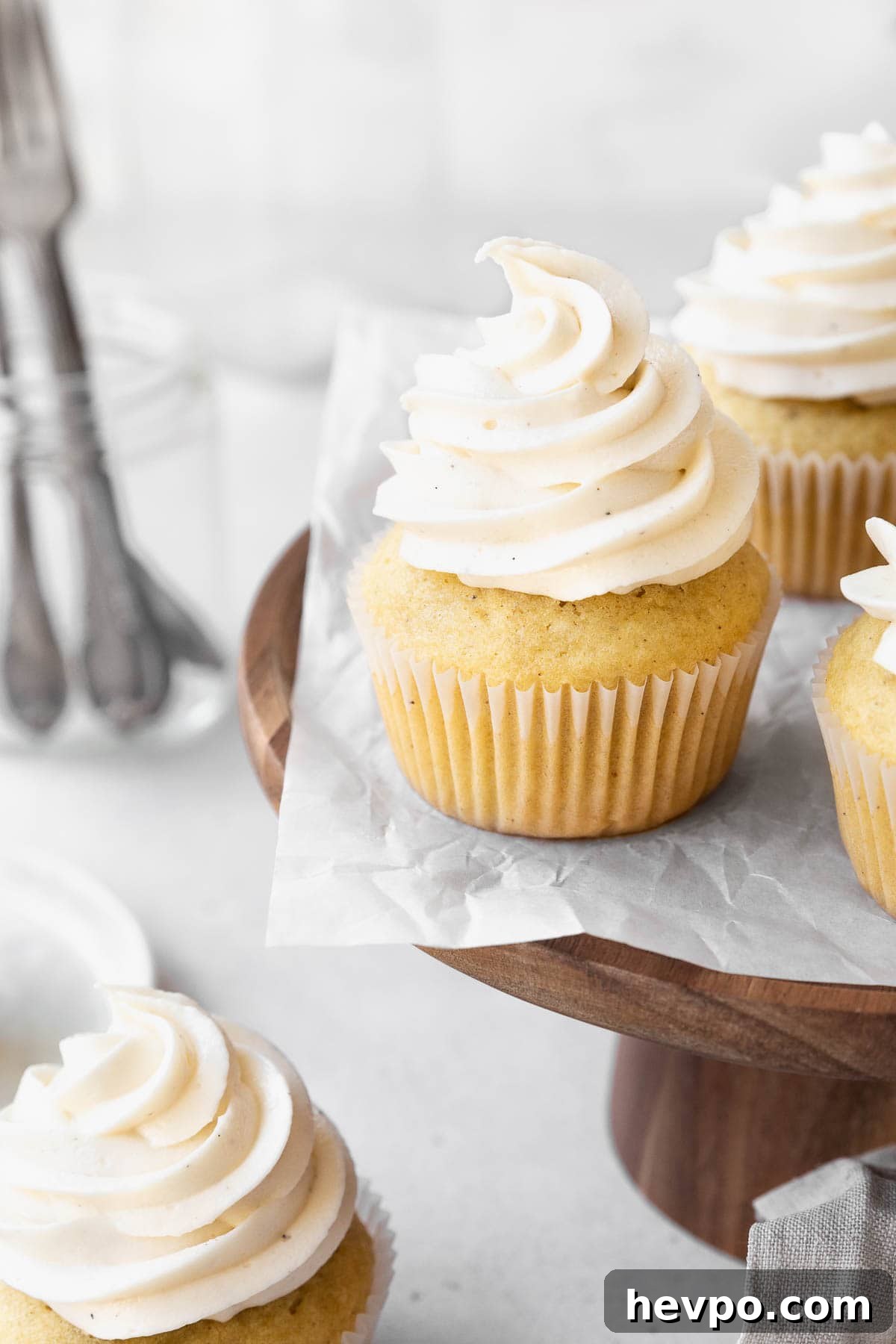 Wooden cake stand with dairy-free buttercream topped vanilla cupcakes.