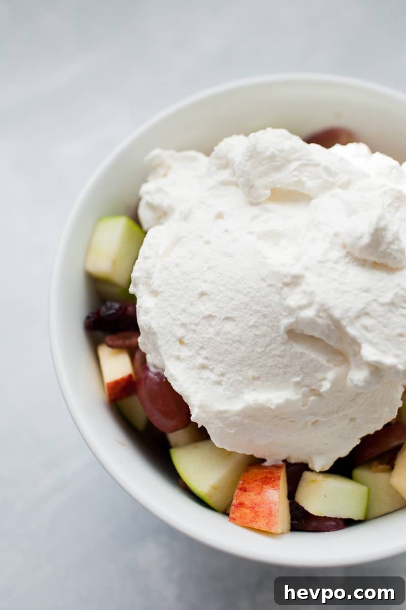 Homemade whipped cream set on top of a bowl of fresh cut fruit.