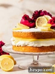Victoria sponge topped with powdered sugar, lemon slices, and peonies