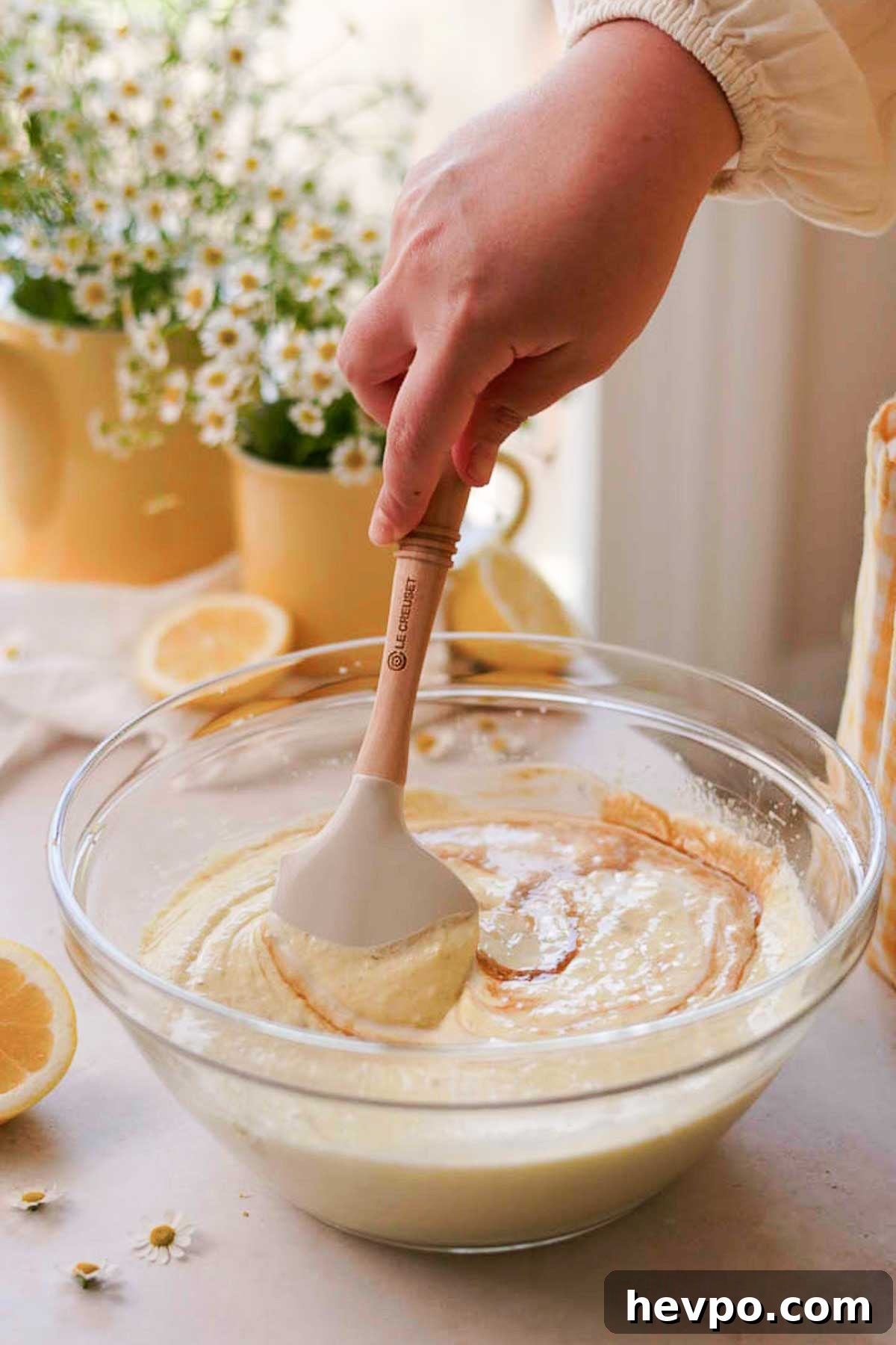 Moist Lemon Poke Cake Recipe with Zesty Lemon Glaze 8 using a spatula to stir the wet ingredients for the lemon batter in a glass bowl