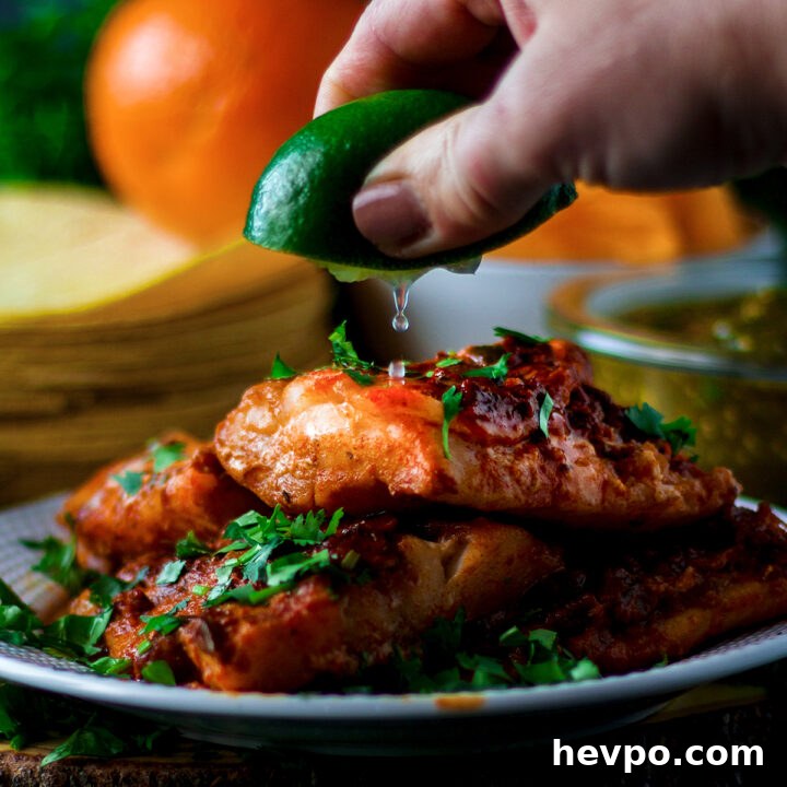 Someone squeezing lime juice over a plate of adobo fish.