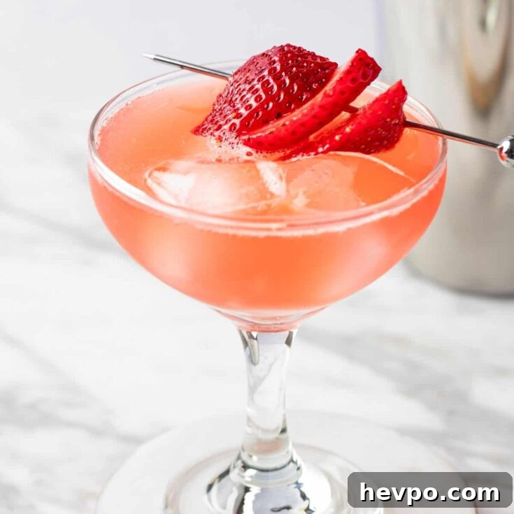 A Strawberry Daiquiri On The Rocks garnished with strawberry slices.