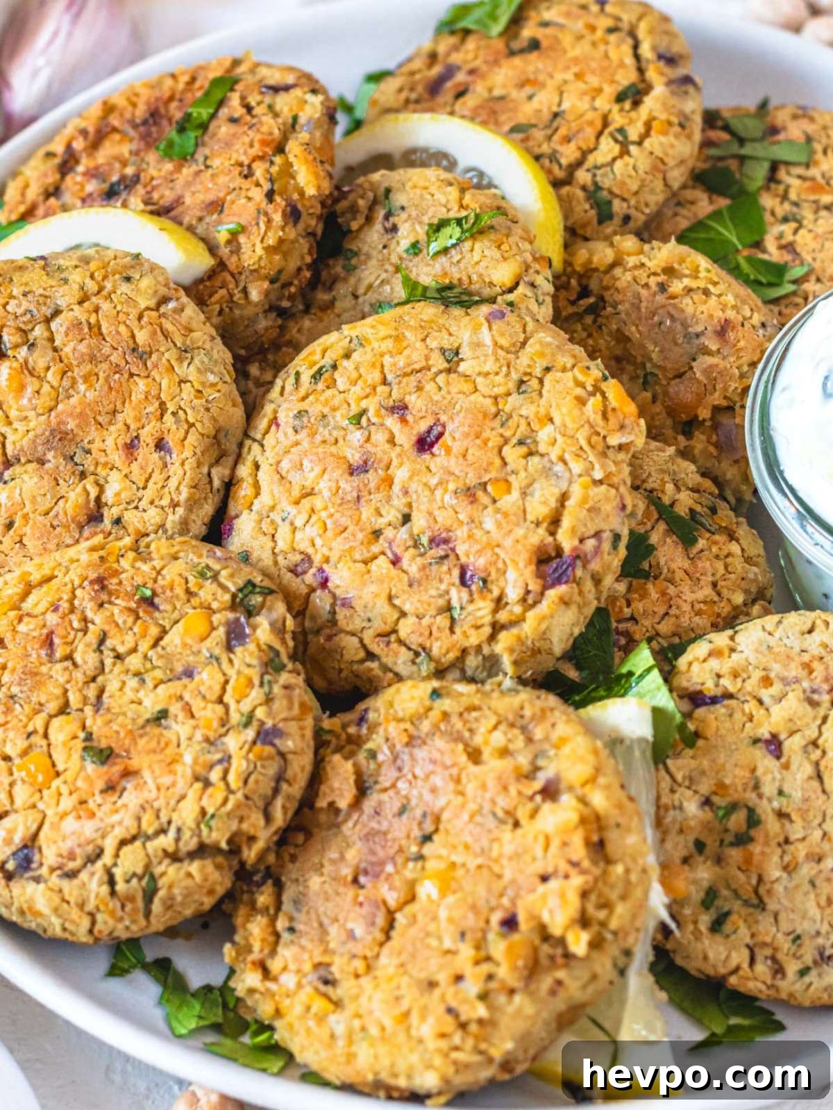 Close up crispy Greek chickpea patties stacked on a plate with fresh herbs.
