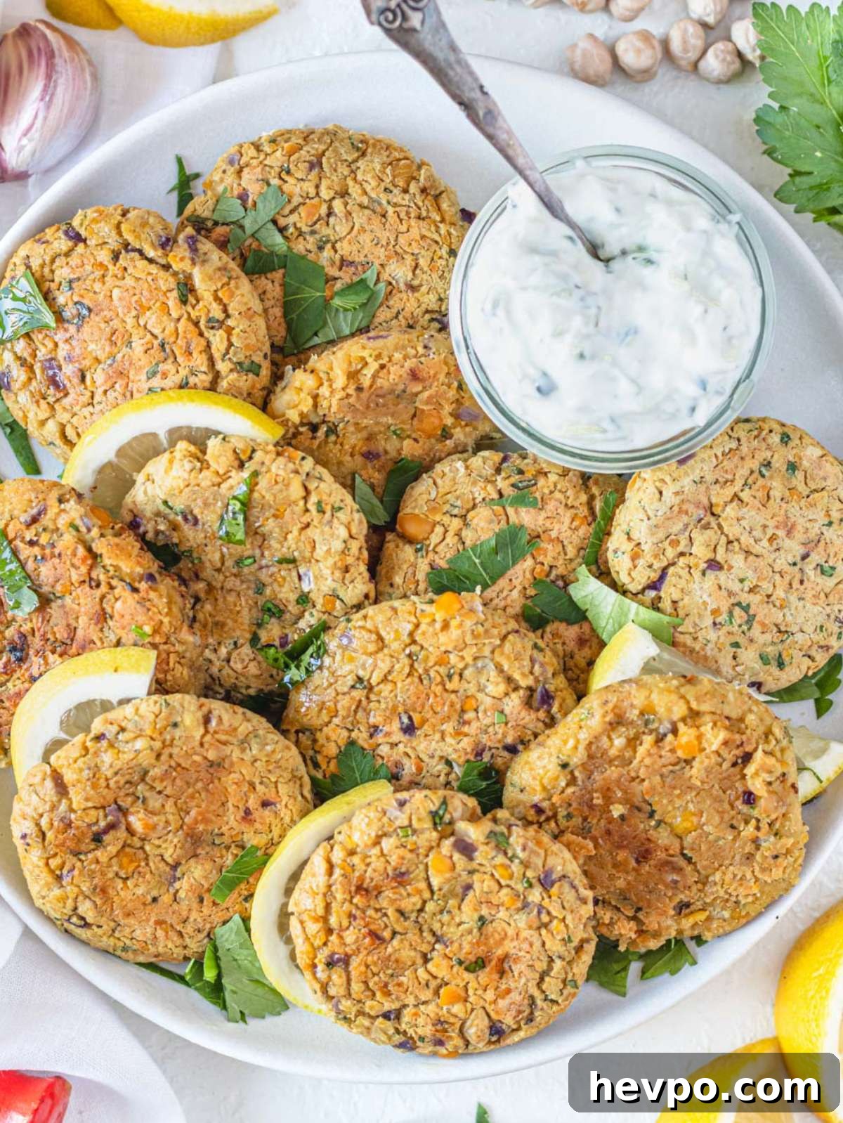 Top down view of golden brown Greek chickpea patties served with lemon wedges.