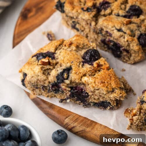 Freshly baked pecan blueberry scones on a wooden cutting board.