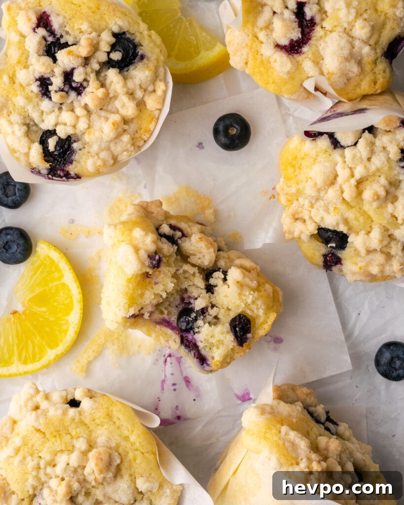 Gluten-Free Lemon Blueberry Muffins Recipe (Moist & Zesty) 10 Half eaten lemon blueberry muffin on a white table.
