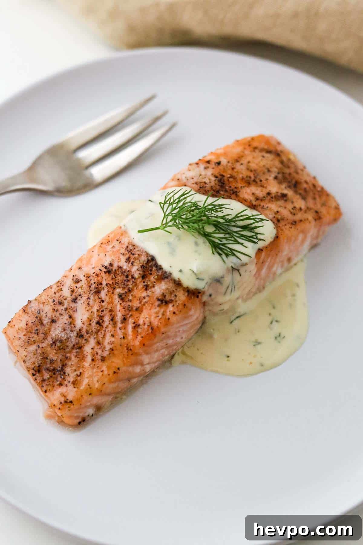 Baked salmon on a plate topped with Warm Mustard Dill Sauce.