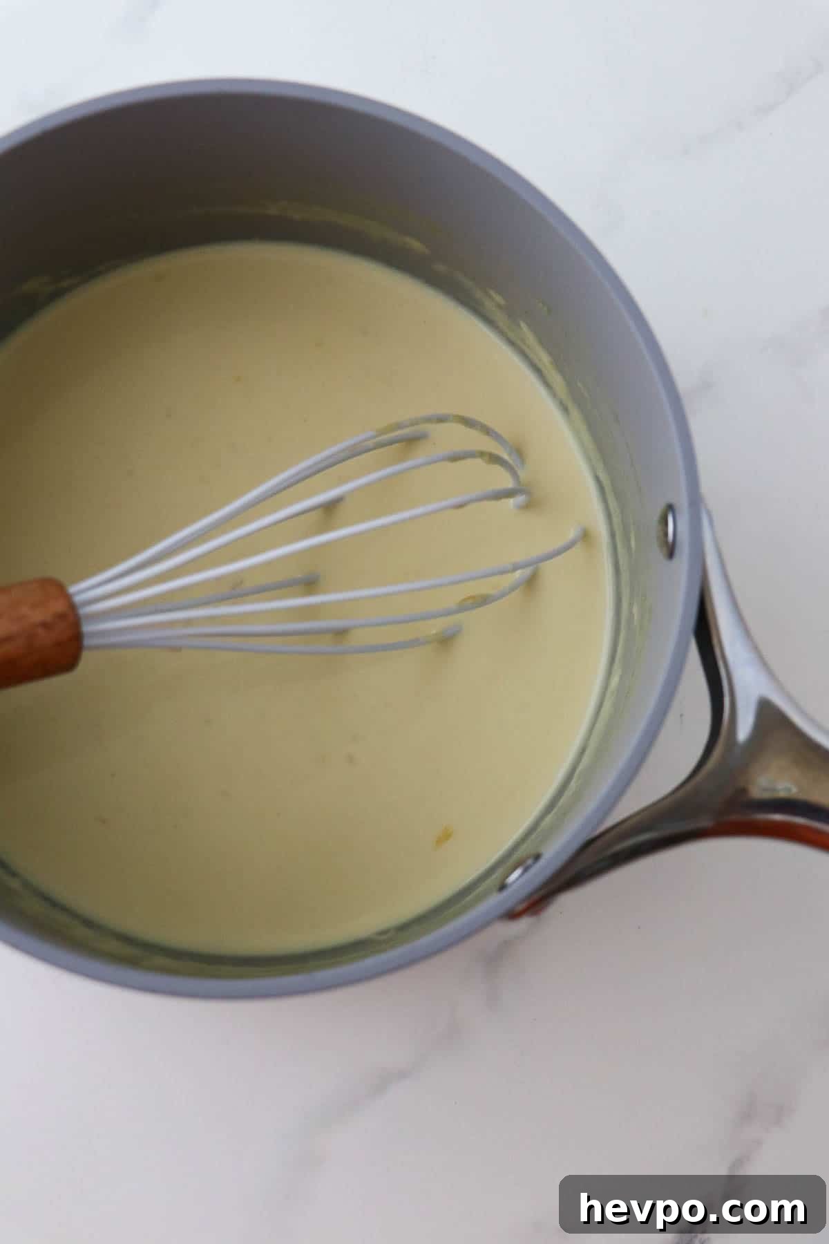 Mustard sauce in a saucepan with a whisk.