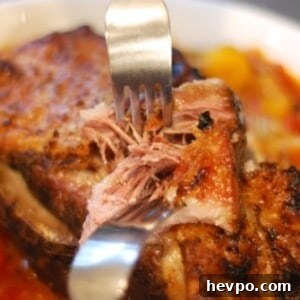 A bowl of slow cooker pork pot roast in a bowl with someone shredding the meat with two forks.