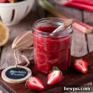 Small-Batch Strawberry Rhubarb Jam Recipe for Perfect Preserves 11 Strawberry rhubarb jam on a wood board with fruit scattered around it.