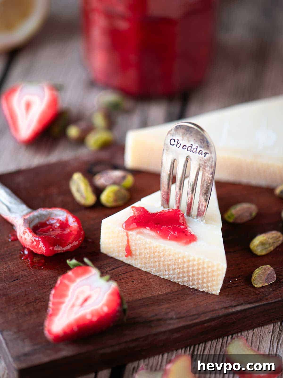 Small-Batch Strawberry Rhubarb Jam Recipe for Perfect Preserves 6 Strawberry rhubarb jam on a wedge of cheese on a wooden board.