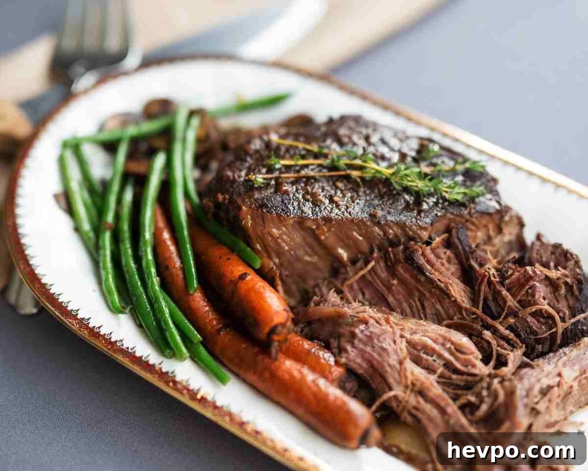 Slow-Cooked Crockpot Chuck Roast Recipe for Tender Beef 3 a platter with pot roast and carrots with green beans.