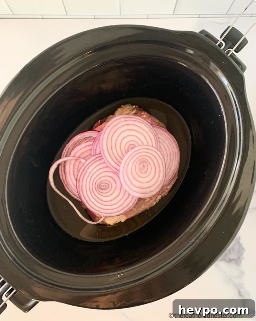 Slow-Cooked Crockpot Chuck Roast Recipe for Tender Beef 5 the crock pot roast with ranch dressing is in the slow cooker, covered with sliced onions in beef broth