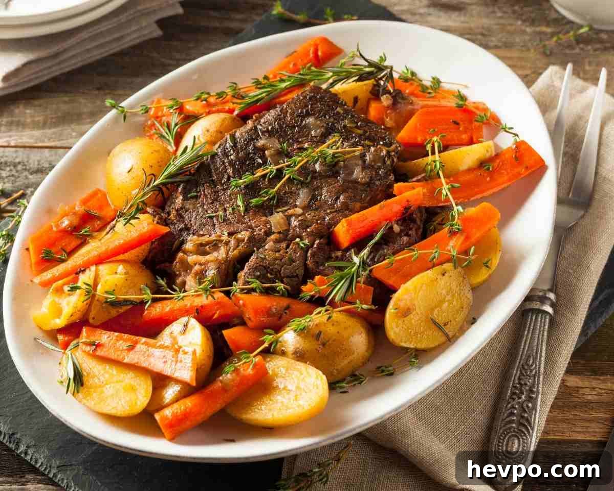 Slow-Cooked Crockpot Chuck Roast Recipe for Tender Beef 7 a plate with pot roast and vegetables with a serving platter in the background