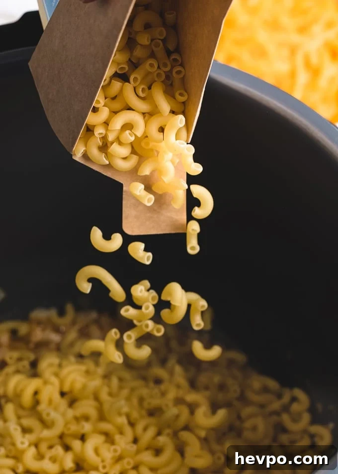 elbow macaroni being poured from a box into an Instant Pot