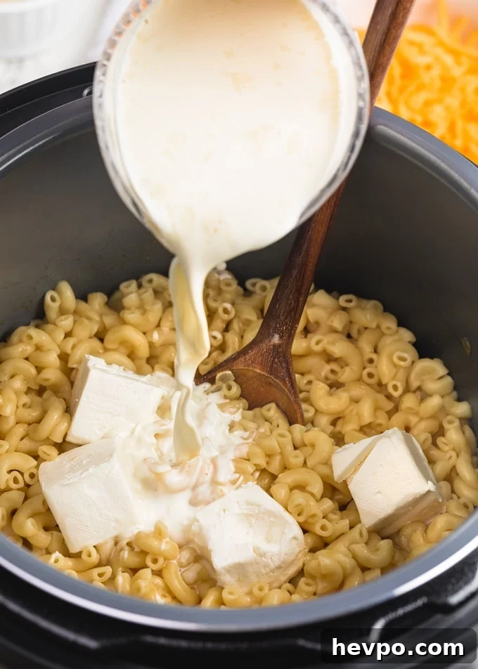 pouring heavy cream into macaroni and cheese in the Instant Pot