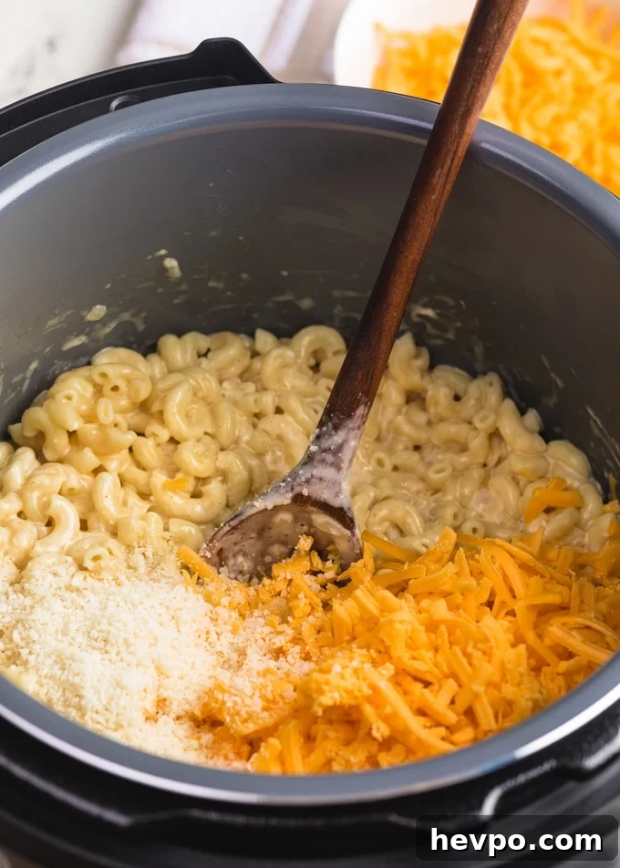 grated cheddar and parmesan cheese being stirred into elbow macaroni