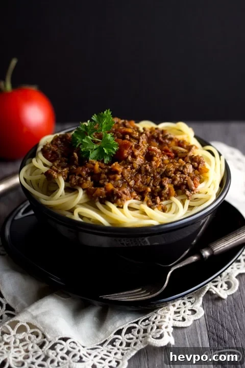 Easy spaghetti bolognese in a black bowl with a fork, topped with parsley