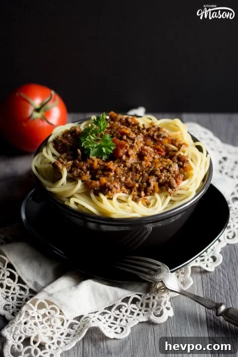 Easy spaghetti bolognese in a black bowl with a fork, topped with parsley