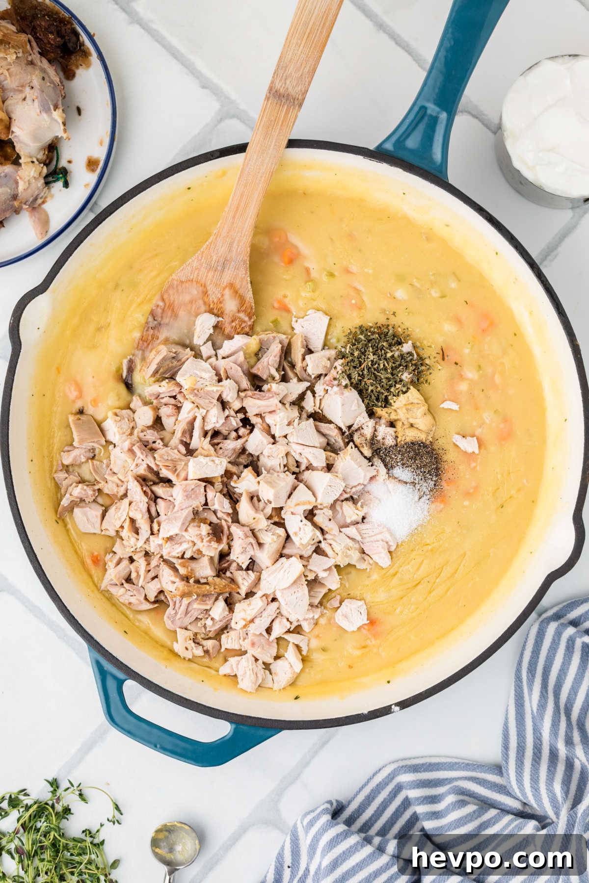 A large skillet with a gravy, chopped chicken and seasonings added.