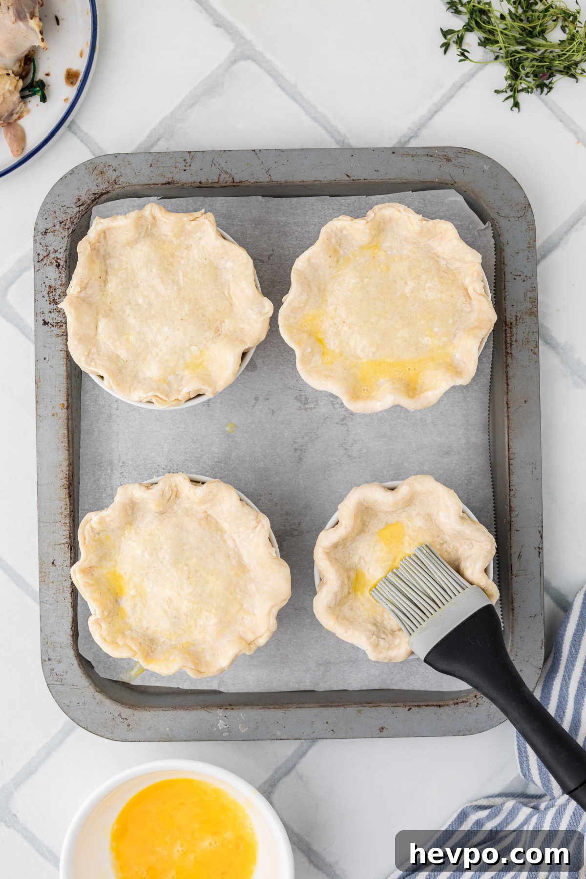 Mini chicken pot pies being brushed with egg.