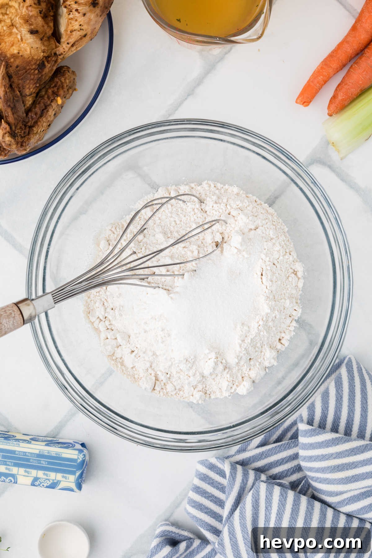 A large mixing bowl with flour and a whisk.