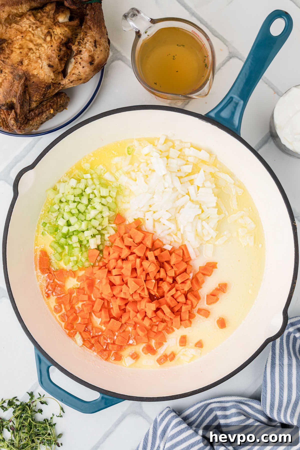 A large heavy skillet with butter, onions, carrots and celery.