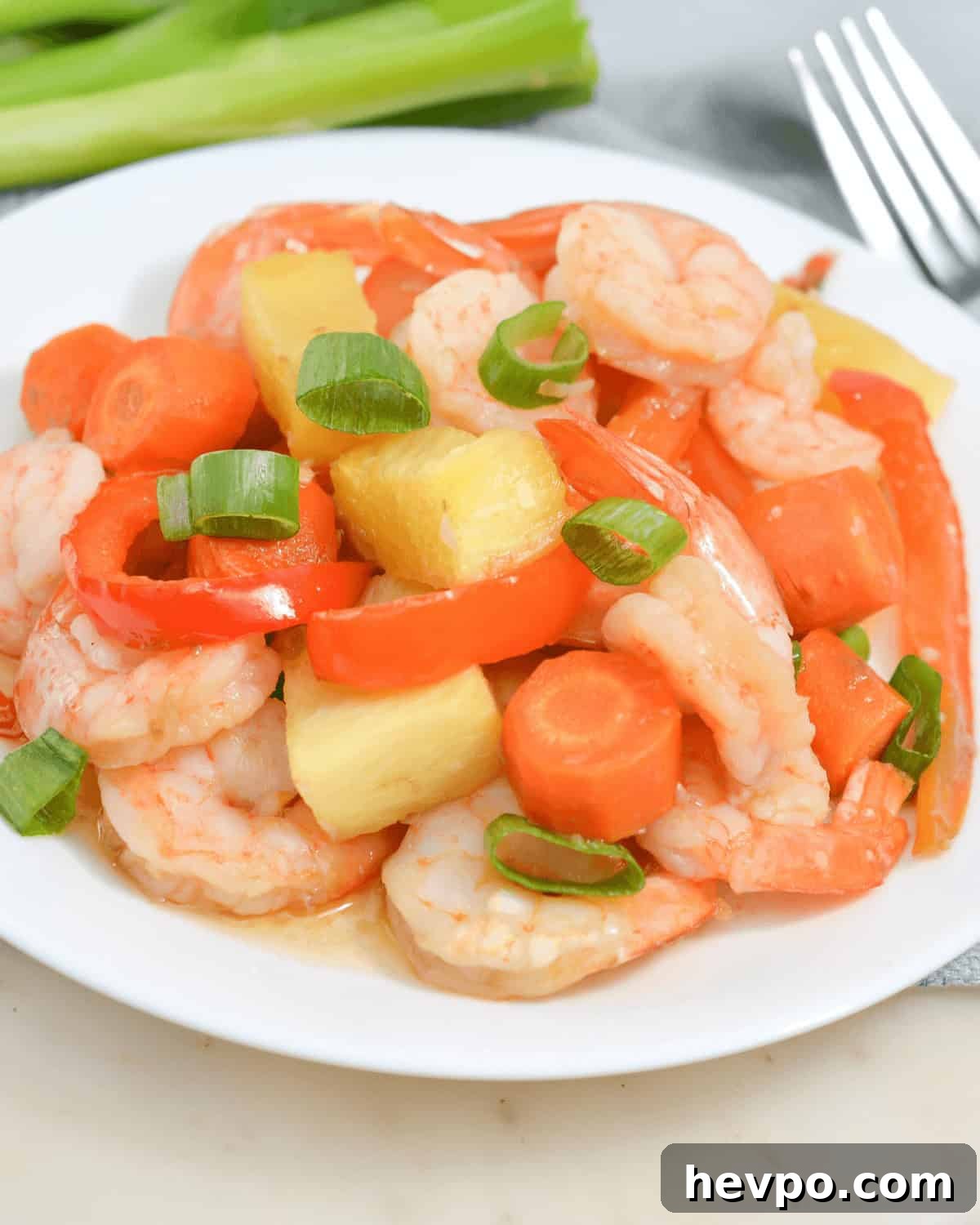 A sheet pan meal featuring succulent shrimp, crisp carrots, and crunchy celery on a white plate.
