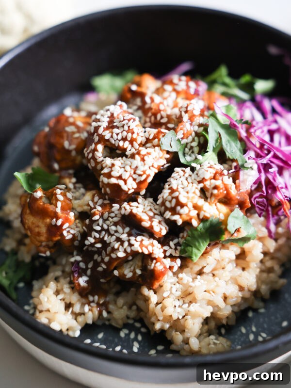 Crispy Air Fryer Sweet Potato Wedges Recipe 12 A closeup shot of the orange cauliflower with rice, red cabbage, and cilantro in a black bowl.