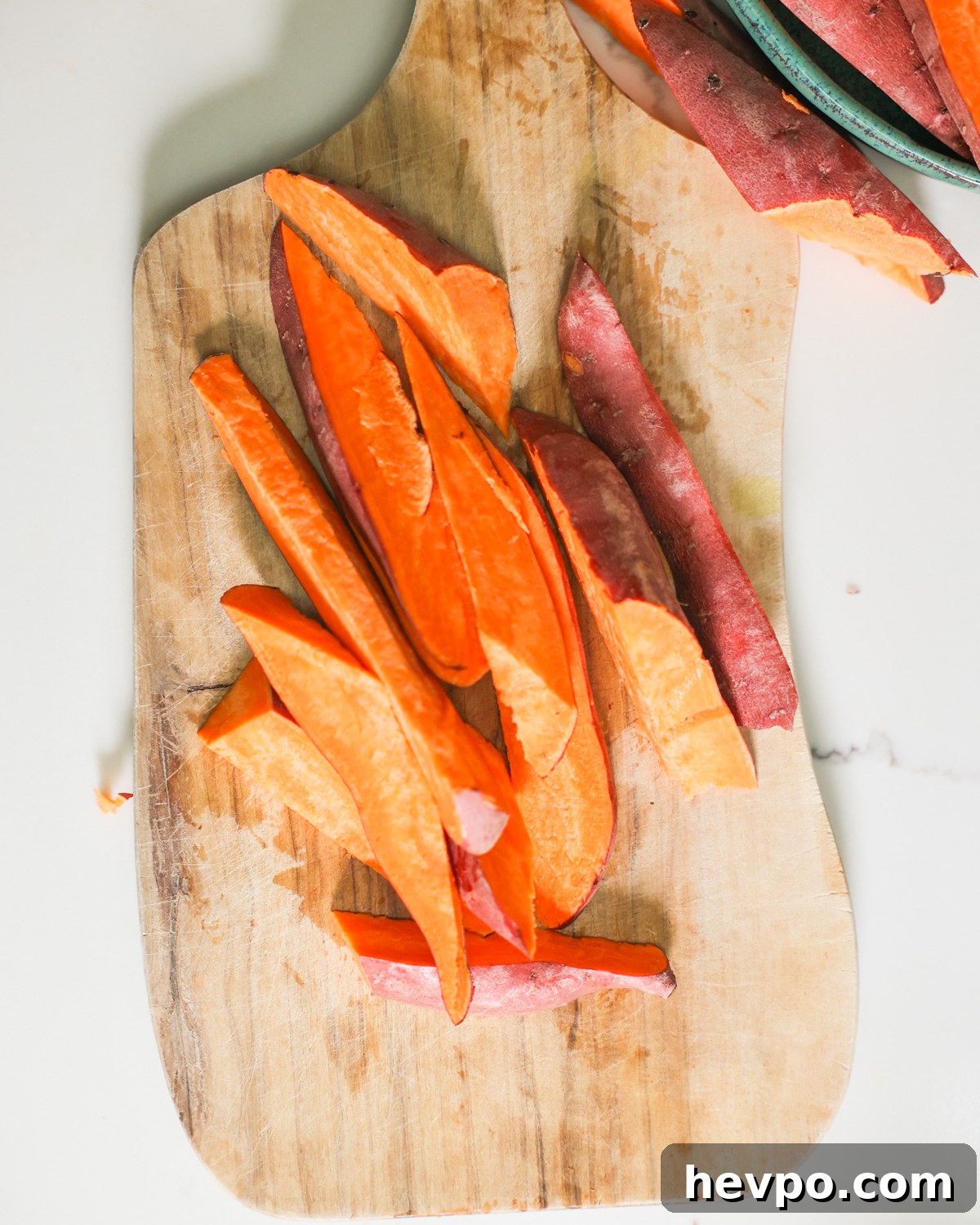 Crispy Air Fryer Sweet Potato Wedges Recipe 5 sliced sweet potatoes on a cutting board