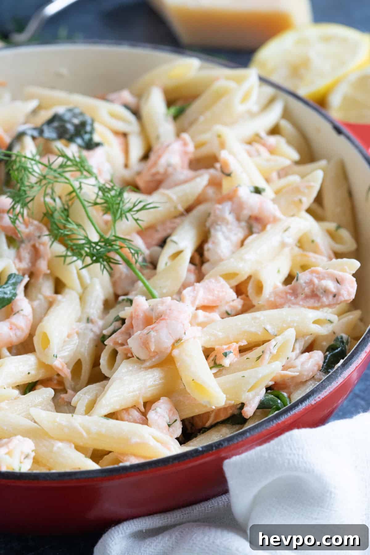 Salmon and prawn pasta in a red pan.