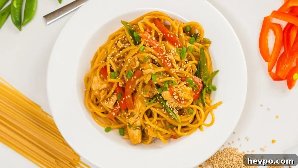 Homestyle Chicken Noodle Stir-Fry That Beats Takeout 2 Chicken noodle stir fry in a white bowl, garnished with sesame seeds and green onion.