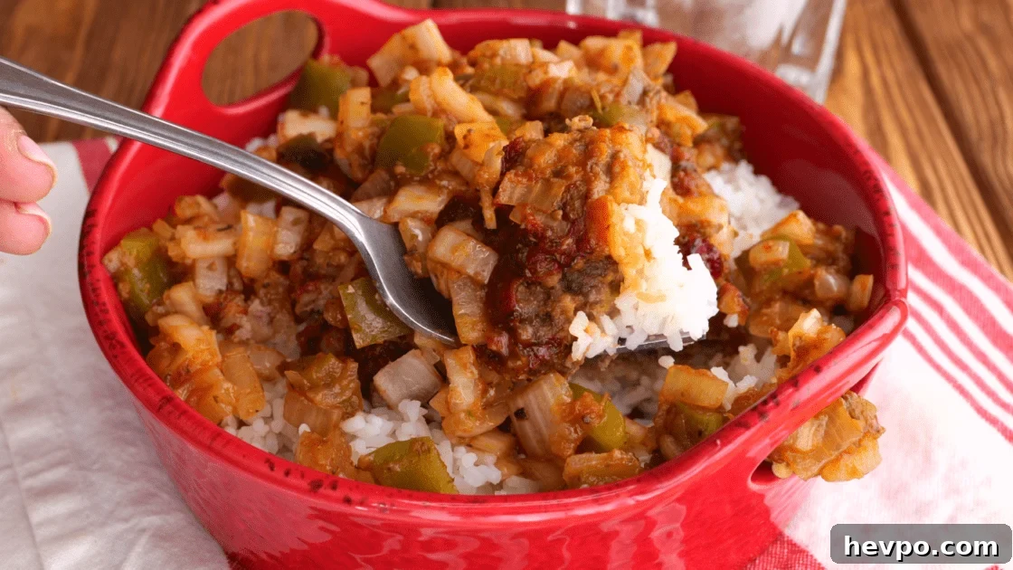 Forkful of hamburger patties with gravy and rice.