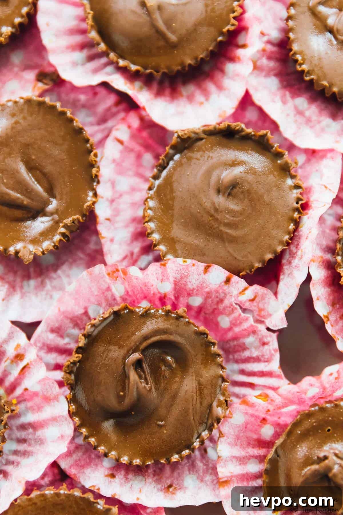Top down shot of pumpkin chocolate cups on pink liners.